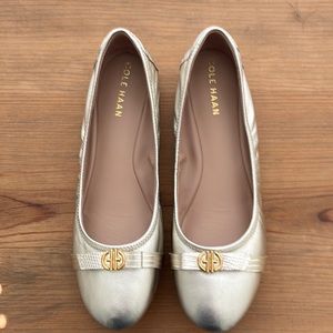 A pair of Cole Haan women’s shoes..Size 8/1/2 B.Silver Color with Gold Trim..